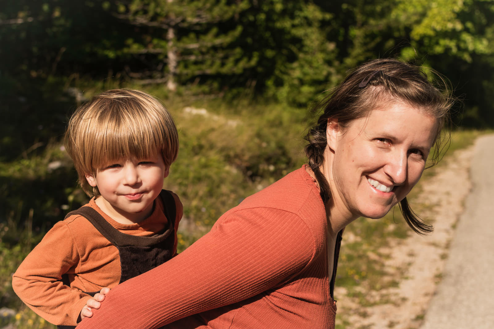 Über mich - Eine junge Frau trägt ein Kleinkind huckepack